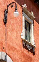 Antique street lamp stands illuminated on a stone wall backdrop with an arched window.