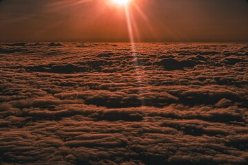 Poster - Scenic view of a sky filled with dark clouds illuminated by the bright sun in the background.