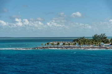 Canvas Print - View from the sea of green tropical trees on the shore of tropical island under blue cloudy sky