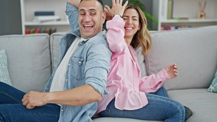 Canvas Print - Man and woman couple sitting on sofa together laughing a lot at home