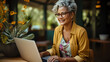 © Yuliia - medium-sized lady with glasses smiles in front of a laptop, a successful well-groomed lady of the age masters the Internet working online from home