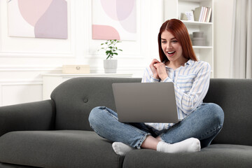 Wall Mural - Happy woman with laptop sitting on couch in room