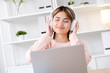 © mangpor2004 - Young asian woman with headphones while working with laptop computer at home office