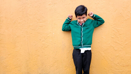 Wall Mural - Dark-haired 9-year-old Latino boy in a public school uniform is excited and happy about the return to school ready to study