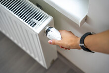 A Woman's Hand Turns The Battery Heating Knob. Heating In An Apartment, At Home. Heating Prices.
