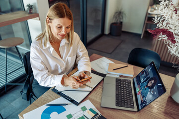 Wall Mural - Business woman freelancer have video conference with client and use phone while sitting in cafe