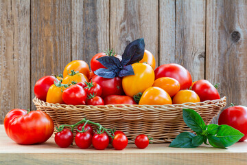 Wall Mural - Fresh ripe tomatoes in a wicker basket on a wooden table