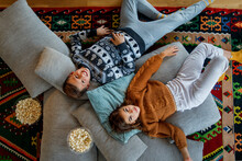 Brother And Sister Lying On Pillows Over Carpet In Living Room