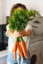 Woman Holding Bunch Of Carrots In Kitchen