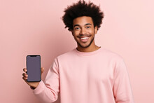 Happy African American Teen Student Holding Mobile Cell Phone Pointing Finger At Smartphone Mock Up Big Screen Template Presenting Application, Using Cellphone Showing Ad Isolated On Beige Background.