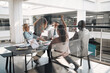 © Flamingo Images - Cheering group of diverse businesspeople meeting around an office table