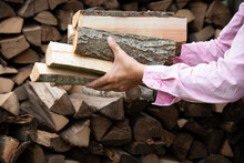 Preparing For The Heating Season With Wood Heating. Firewood In The Hands Of Woman