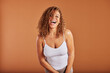 © Flamingo Images - Young woman in a tank top laughing on an orange background