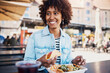 © Flamingo Images - Young woman smiling and eating tacos on the patio of a restaurant