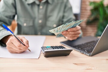 Young man ecommerce business worker holding brazil real banknotes write on paper at office