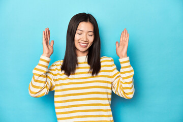 Wall Mural - Asian woman in striped yellow sweater, joyful laughing a lot. Happiness concept.
