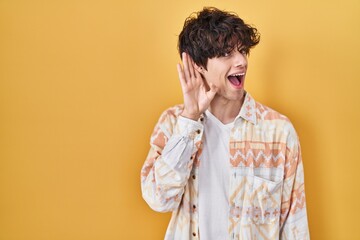 Poster - Young man wearing casual summer shirt smiling with hand over ear listening an hearing to rumor or gossip. deafness concept.