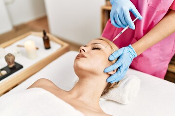 Poster - Young caucasian woman lying on table having antiaging treatment at beauty salon