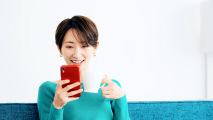Leinwandbilder - リビングでスマホを見る女性