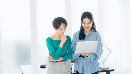 Leinwandbilder - オフィスでノートパソコンを見ながら話す二人の女性