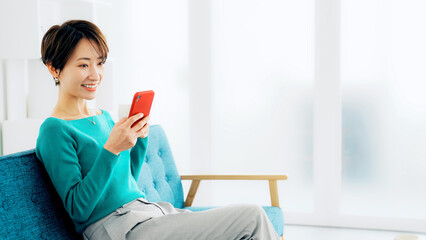 Leinwandbilder - リビングでスマホを見る女性