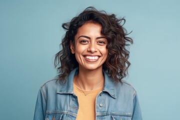 Wall Mural - Portrait of a smiling young woman with curly hair isolated over blue background