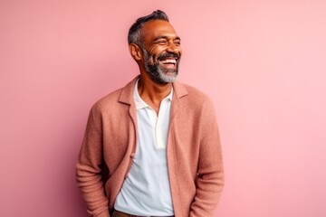 Wall Mural - Portrait of a mature Indian man smiling on a pink background.