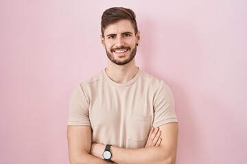 Poster - Hispanic man with beard standing over pink background happy face smiling with crossed arms looking at the camera. positive person.