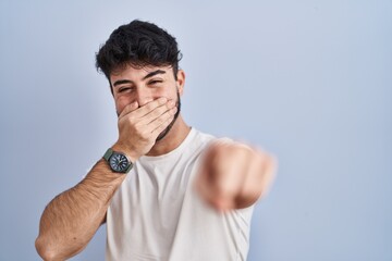 Canvas Print - Hispanic man with beard standing over white background laughing at you, pointing finger to the camera with hand over mouth, shame expression