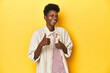 © Asier - African woman, beige shirt, red striped tee, yellow studio, raising both thumbs up, smiling and confident.