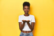 © Asier - African woman, white tee, short hair, yellow studio, holding something with palms, offering to camera.