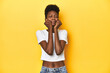 © Asier - African woman, white tee, short hair, yellow studio, crying, unhappy with something, agony and confusion concept.