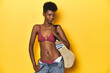 © Asier - Happy African woman in bikini with beach bag ready for vacation.