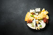Cheese platter with craft cheese assortment and grape at black background. Top view with copy space.