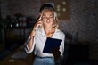 © Krakenimages.com - Young blonde woman working at the office at night shooting and killing oneself pointing hand and fingers to head like gun, suicide gesture.