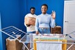 © Krakenimages.com - Young african american couple hanging clothes at clothesline doing ok sign with fingers, smiling friendly gesturing excellent symbol