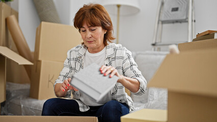 Sticker - Middle age woman unpacking cardboard box at new home