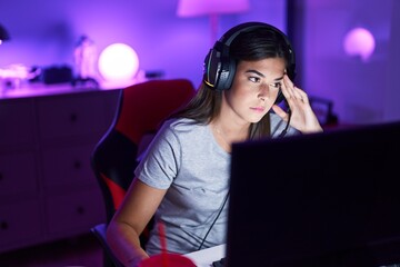 Wall Mural - Young beautiful hispanic woman streamer playing video game using computer at gaming room