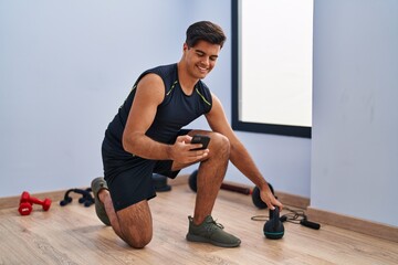 Sticker - Young hispanic man using kettlebell and smartphone training at sport center