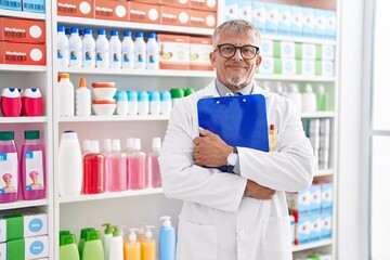 Canvas Print - Middle age grey-haired man pharmacist smiling confident hugging clipboard at laboratory