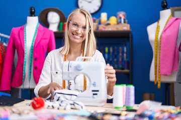 Sticker - Young blonde woman tailor smiling confident using sewing machine at sewing studio