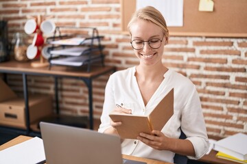 Poster - Young blonde woman business worker using laptop writing on notebook at office