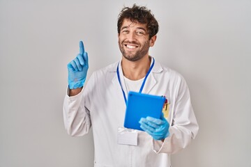 Canvas Print - Hispanic scientist man working with tablet surprised with an idea or question pointing finger with happy face, number one