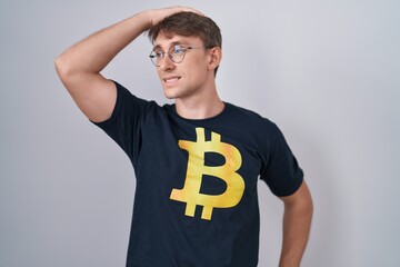 Poster - Caucasian blond man wearing bitcoin t shirt smiling confident touching hair with hand up gesture, posing attractive and fashionable