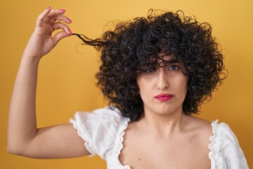 Sticker - Young brunette woman with curly hair holding curl skeptic and nervous, frowning upset because of problem. negative person.