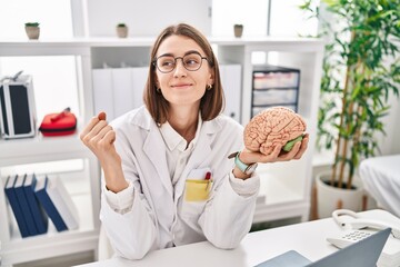 Canvas Print - Young caucasian doctor woman holding brain as mental health concept screaming proud, celebrating victory and success very excited with raised arms