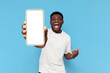 © Богдан Маліцький - african american guy in white t-shirt shows blank screen of smartphone and rejoices in victory on blue background