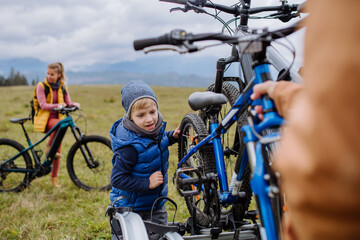 Wall Mural - Littlle boy helping father attache a bicycle on bike carrier.