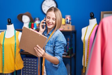 Canvas Print - Young blonde woman tailor talking on smartphone reading document at sewing studio