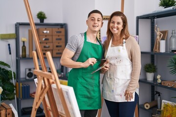 Wall Mural - Man and woman artists smiling confident holding paintbrush and palette at art studio